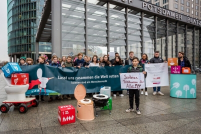 Eine Schulgruppe hält ein Banner in die Kamera mit der Aufschrift "Lass uns zusammen die Welt retten - Toiletten sind ein Menschenrecht"