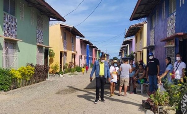 Personen stehen in der MItte einer Straße mit bunten Häusern.