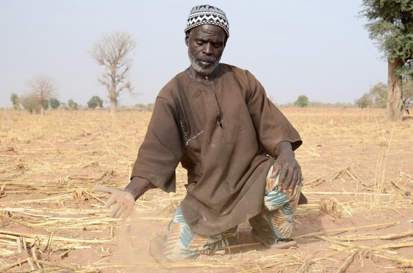 Ein Mann in Mali hält trockene Erde in der Hand.