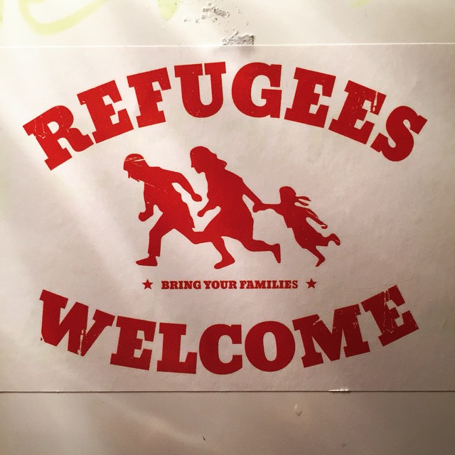 Aufkleber auf Laternenpfahl mit Schriftzug Flüchtlinge Willkommen