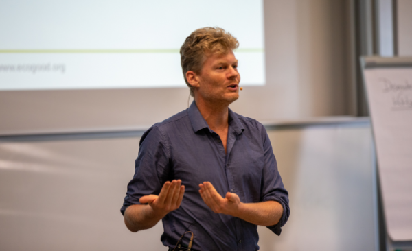 Christian Felber steht in einem Hörsaal vor einer Präsentation und spricht. Foto: Hochschule Harz