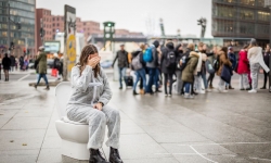 Eine Schülerin sitzt in einem weißen Overall auf einer Toilettenschüssel mitten auf dem Potsdamer Platz in Berlin.